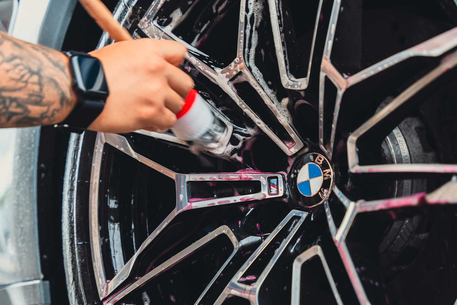 detailer brushing bmw wheels with iron remover on them